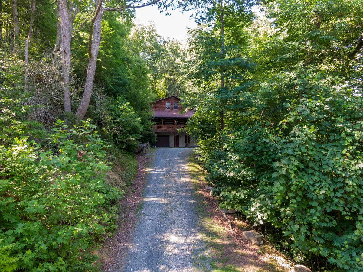 This image showcases the exterior of the house framed by surrounding trees, with the driveway and a peaceful natural setting. The house appears welcoming and nestled in nature, offering an inviting starting point for family adventures.