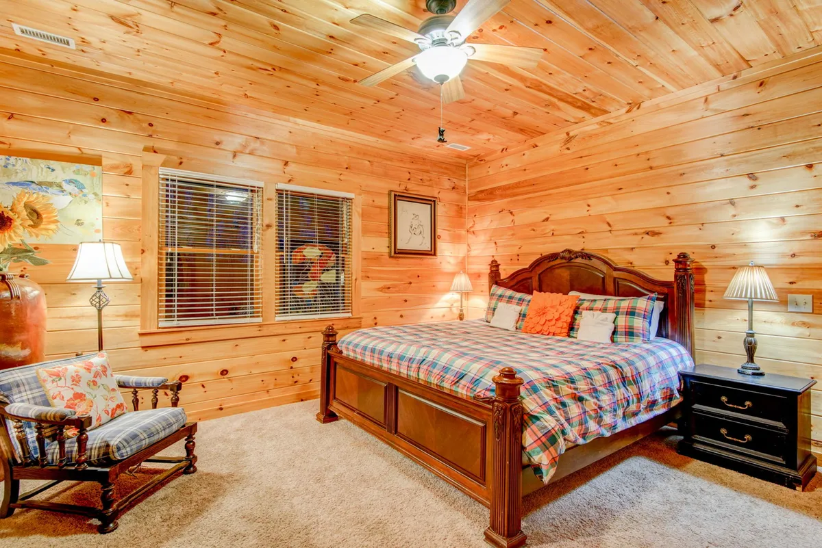 A welcoming bedroom furnished with a comfortable bed, an armchair positioned by the window, soft lamps, and tasteful artwork. The space is bathed in gentle light, ideal for both relaxing and enjoying quiet moments alone or with loved ones.