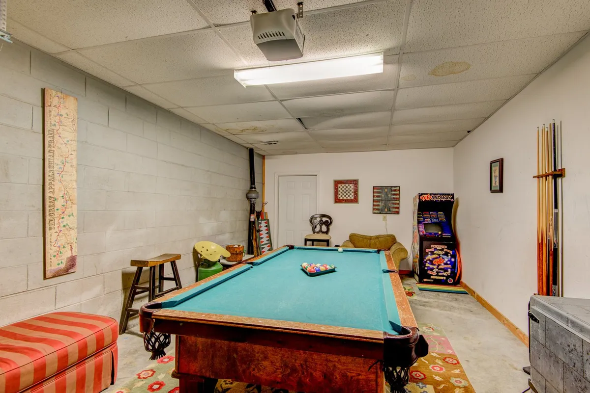 This interior image showcases a vibrant game room equipped with a pool table, arcade game, comfortable seating, and decorative wall art. The space is designed for playful interaction and social gatherings, emphasizing its role as the entertainment hub of the home.